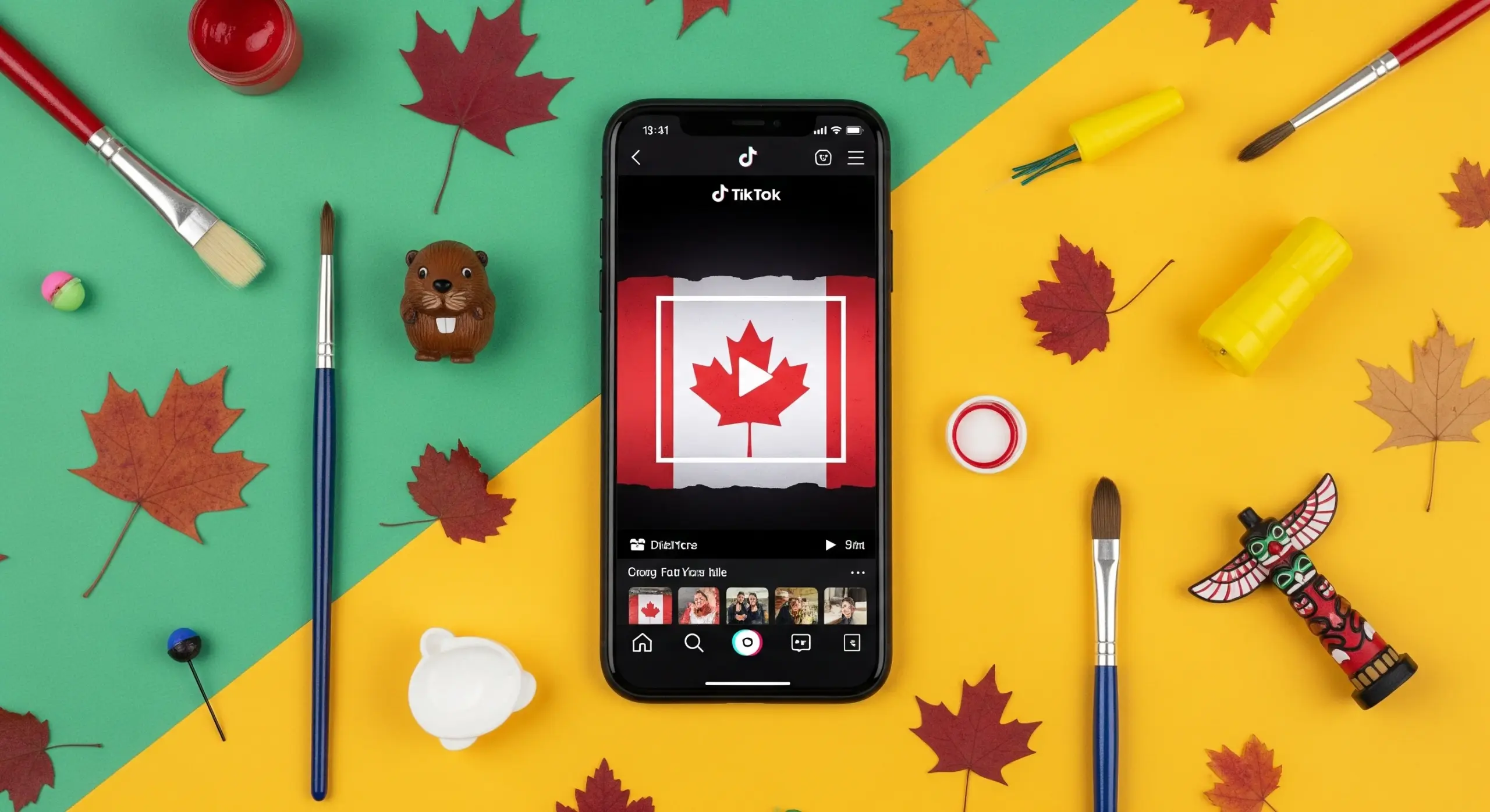 A photo of a smartphone displaying the TikTok app with a Canadian flag on screen, surrounded by maple leaves and art supplies.